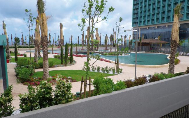 Un parque sobre un garaje subterranéo con piscinas y palmeras
