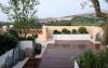 Terraza con pavimentos de madera y olivos, boj y romero en macetas